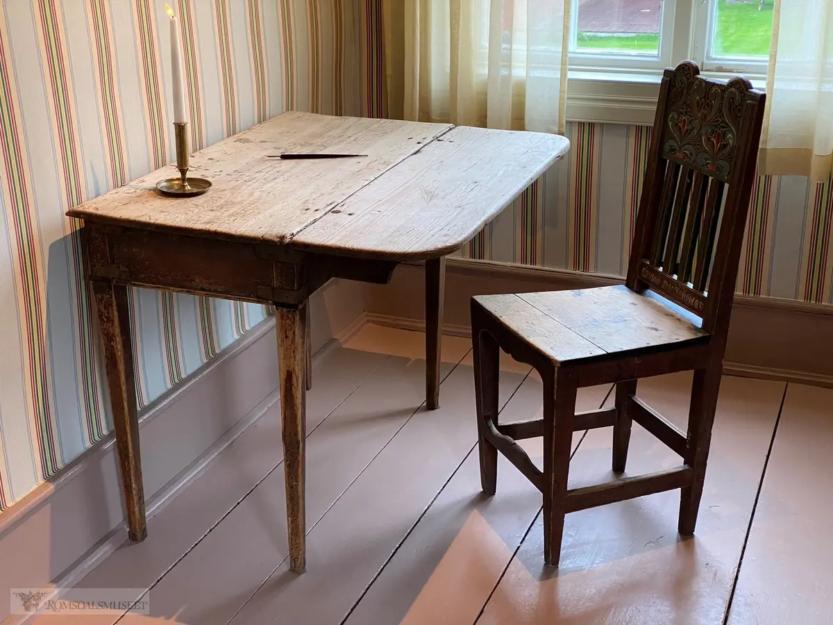 Trebord med avrundet bordplate, og en liten klaff med hengsler og en utskyvbar fot. Bordet har sarg og en skuffe med knott.