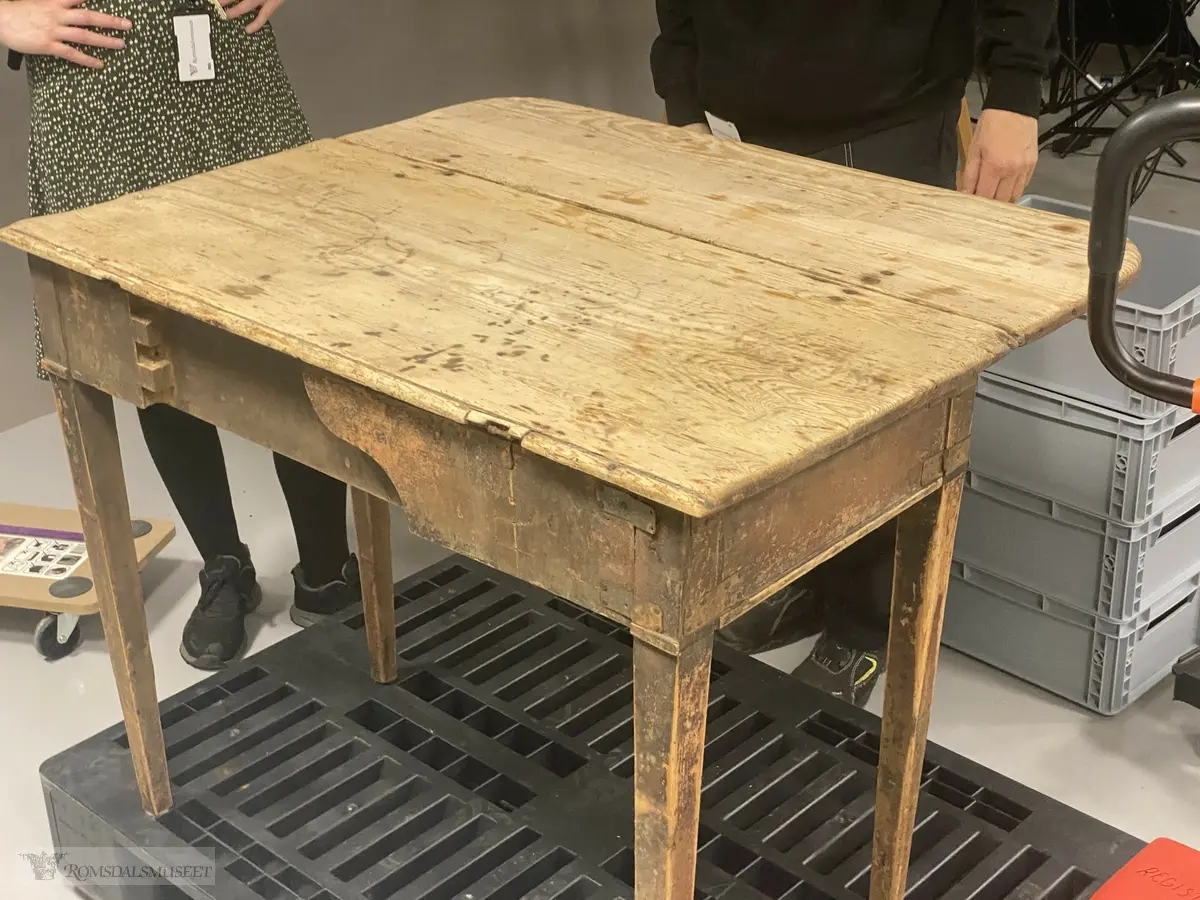Trebord med avrundet bordplate, og en liten klaff med hengsler og en utskyvbar fot. Bordet har sarg og en skuffe med knott.