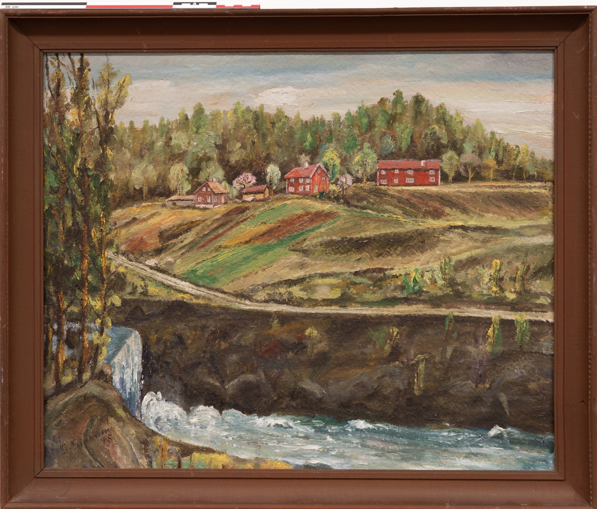 Landskapsmotiv med innhus, uthus, dyrket mark i skrått terreng. Med vei, skog, fjell, elv og demning. Motivet er sett fra motsatt side av Storelva ved Kniphammerdammen.