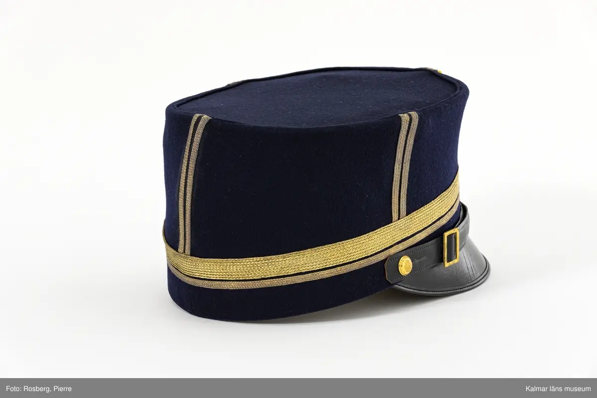 KLM 19048:4:1. Mössa. Käppi. För major. Mössa av mörkblått kläde. Rak i sidorna. Platt kulle. Svart skärm. Fyra st. dubbla stolpar av guldgalon på kullens sidor. Liten kokard av gult siden mitt fram med två plisserade ringar. Blå emaljerad mössknapp med tre kronor, under kokarden. Mössrem av svart skinn med spänne av gulmetall ovanför skärmen, fästs i mössan med liten kulknapp av gulmetall. Två rader guldgalon nära mössans nederkant, en smal och en bred. Svettrem av brunt skinn. Kullen fodrad med blankt satinvävt svart tyg. Tryckt text i guld i kullen: MILITÄR EKIPERINGS A.B. STOCKHOLM M.E.A. samt ägarinitialer  PH. V. K.
Mössan förvarades på kullen i hattask KLM 19048:4:2.