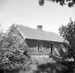 Stugan Back under Rosendal i Järstad. Här dokumenterad av Östergötlands museum 1951. Vid tiden beboddes stugan av Oskar Emil Karlsson och möjligtvis är det honom vi skymtar i dörröppningen. Vy från sydost.