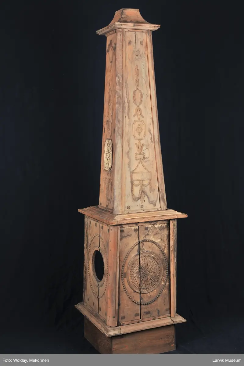 Pyramideovn. Modellplater av ovn kalt "Nr. 14". Delvis satt sammen. Underdelen firkantet med en stor rosett i oval perleramme. Høy, avsmalnende overdel med Louis XVI-ornamenter