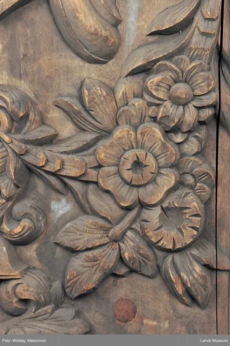 Midtfeltet for påsetting av skrift, omgitt av korsfestelsen, engler, dødssymboler og akantusløv. I hjørnene medaljonger med bilder av de fire evangelister