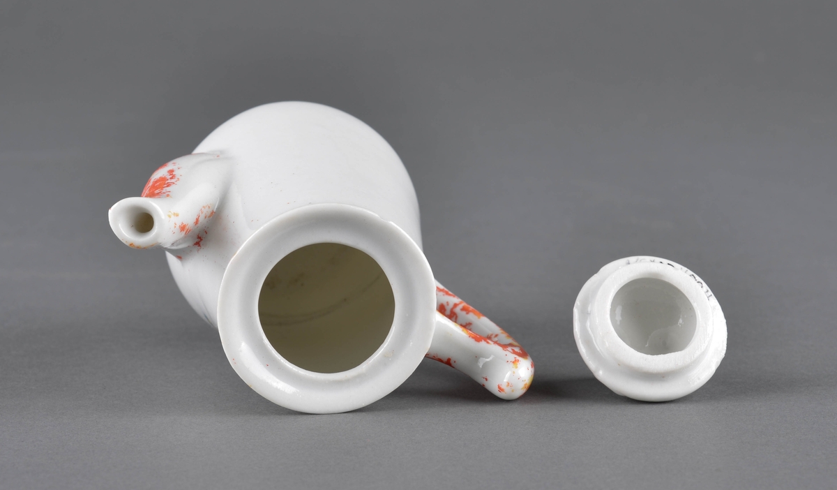 Te- eller kaffekanne med lokk
Kannen har tut og hanke med delvis avslitt rød dekor og et dekorbilde på ene siden, som er delvis slitt av.