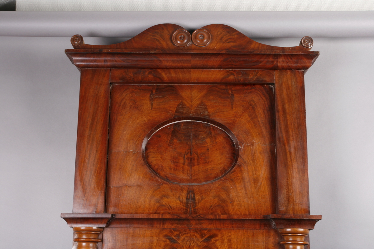 Biedermeier speil i treramme. Innfelt oval dekor på feltet på toppen. Øverst skåret dekor med sirkler. Søyler på hver side av speilet. Mahogny? Polert.