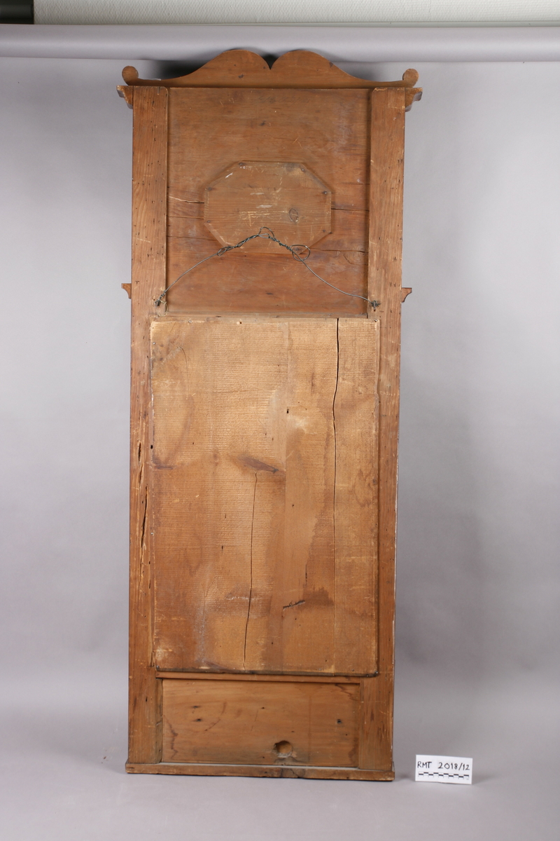 Biedermeier speil i treramme. Innfelt oval dekor på feltet på toppen. Øverst skåret dekor med sirkler. Søyler på hver side av speilet. Mahogny? Polert.