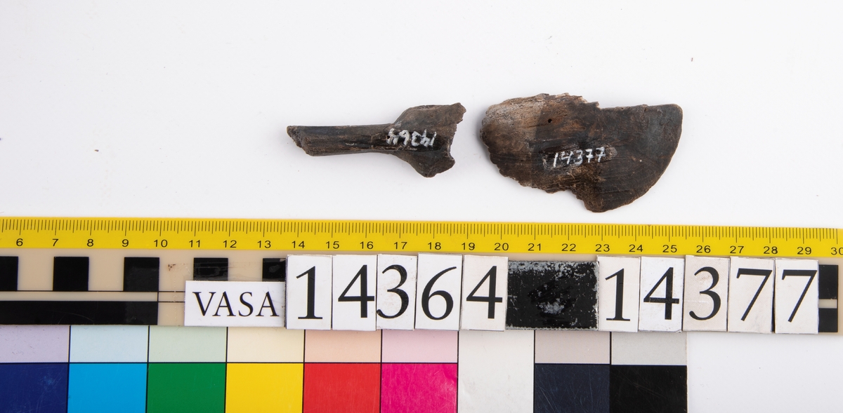 Del av en träsked. Delen utgör större delen av skedskaftet samt mindre parti av skedbladet. Skaftet är rakt och relativt smalt.

Skeddelen är bruten vid skaftänden samt upptill, vid skedbladets nedre del.

För mer information se Dokumentationsblankett under Referenser – Länkade filer.