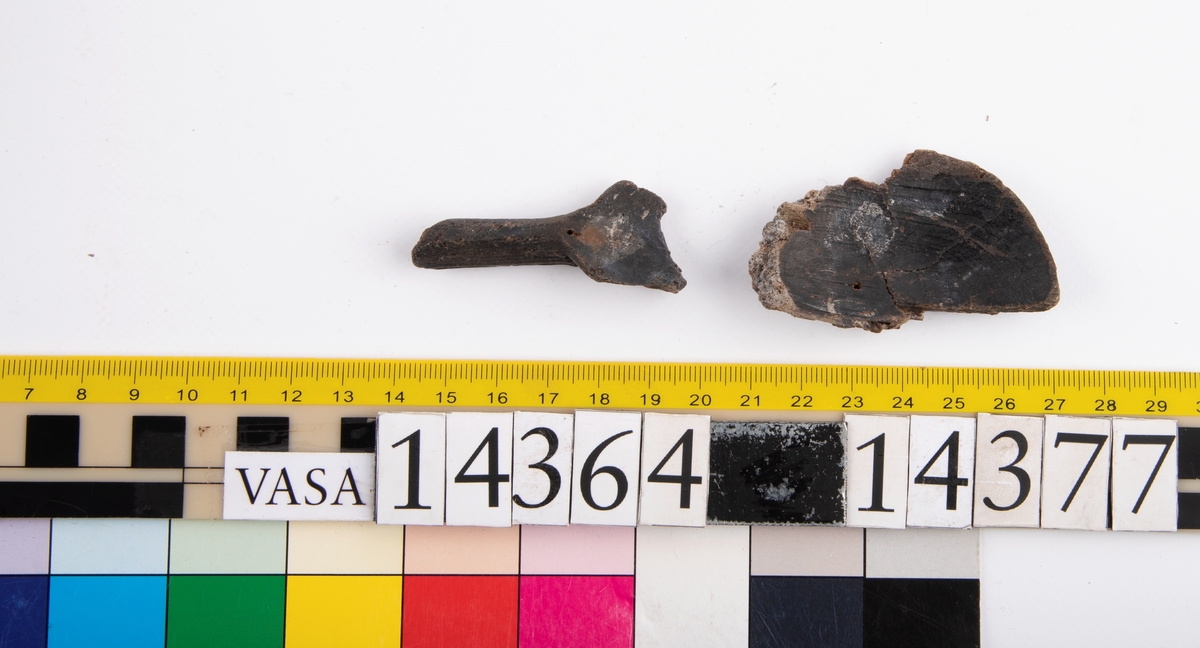 Del av en träsked. Delen utgör större delen av skedskaftet samt mindre parti av skedbladet. Skaftet är rakt och relativt smalt.

Skeddelen är bruten vid skaftänden samt upptill, vid skedbladets nedre del.

För mer information se Dokumentationsblankett under Referenser – Länkade filer.