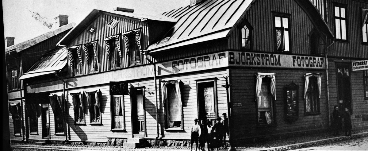 Fotograf Gustaf Björkströms ateljé och bostad på ovanvåningen i huset på hörnet Torggatan-Östra Långgatan. På gaveln sitter hans skyltskåp och till höger om det finns ingången. Han tog över ateljén 1906. I bottenvåningen ligger ett café. Ett gäng gossar står vid husknuten och ett par flickor vid Björkströms entré.