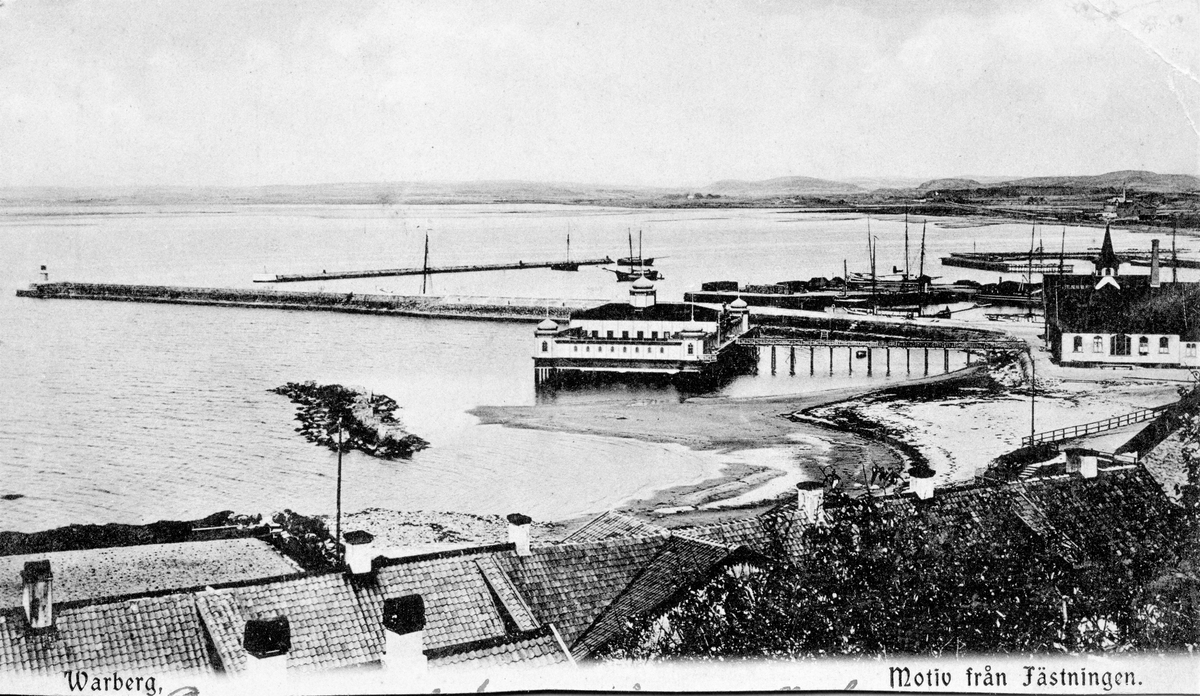 Brevkort, "Warberg. Motiv från fästningen." Utsikt från Varbergs fästning över kallbadhuset till vänster, efter återuppbyggnaden 1903, och varmbadhuset till höger. I förgrunden ses Barnens badstrand och i bakgrunden hamnen. Bilden tagen före 1915.