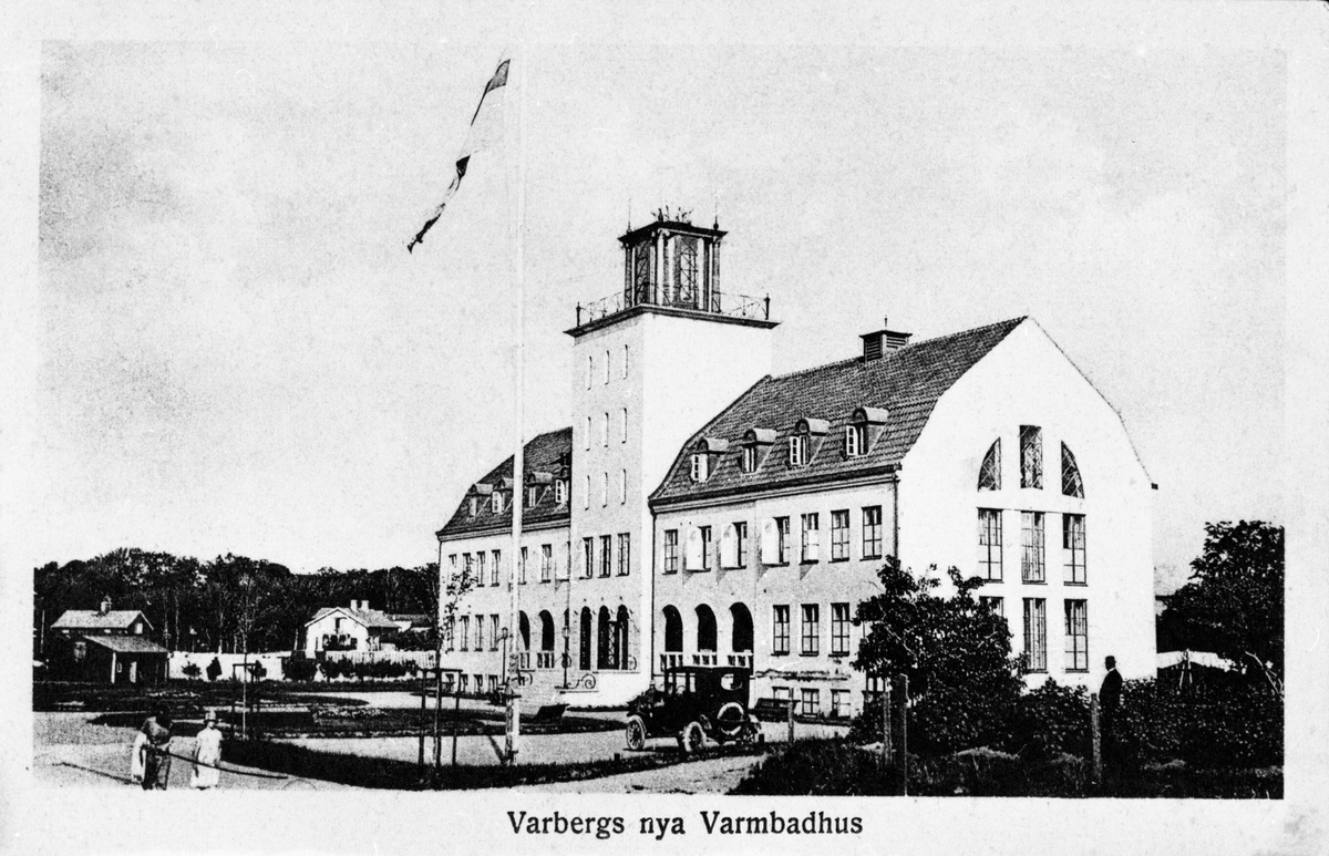 Vykort, två olika versioner av samma fotografi föreställande Varbergs nya varmbadhus, som stod klart 1925. Det äldre från 1866 låg nere vid vattnet, medan detta förlades vid Strandgatan. En bil står parkerad framför badhuset. Kvarteret hette då Styrmannen men uppgår numera i kv Skepparen. (Se även bildnr F1673.)