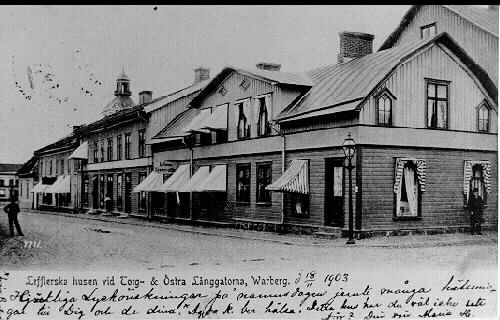 Brevkort, "Lefflerska husen vid Torg- & Östra Långgatorna, Warberg.", daterat den 18 november 1903. (Bild 2 visar även meddelandet på kortet.) Detta är kv Apotekaren utmed Torggatan. Sjöbergs speceriaffär ligger i huset närmast i bild och utmed dess gavel går Östra Långgatan. Där står en man med kubb och käpp vänd mot fotografen. Bilden är tagen mot nordväst.