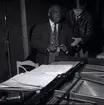 Count Basie och en person vid ett piano, verkar som att CB signerar en sedel.