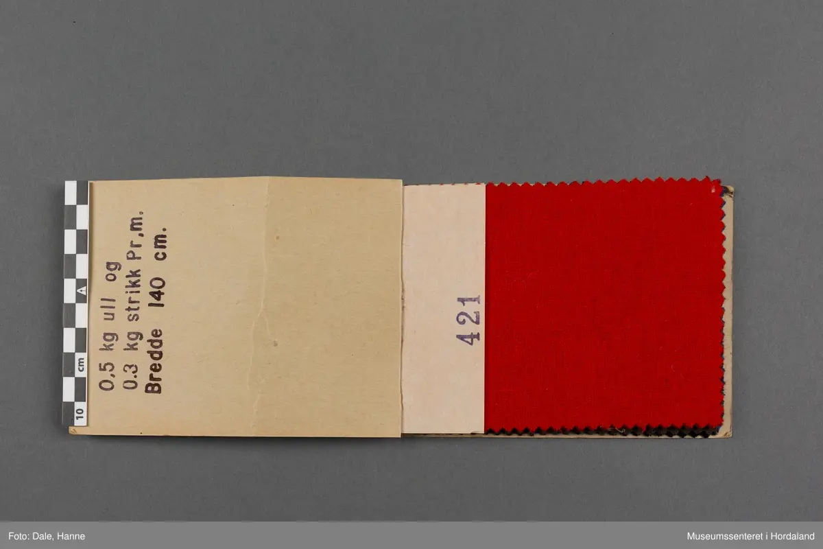 Mappe med rektangulære stoffprøver av vevd ullstoff, einsfarga stoff i ulike fargar. Desse prøvane er til kjoletøy i nr. 421-429.