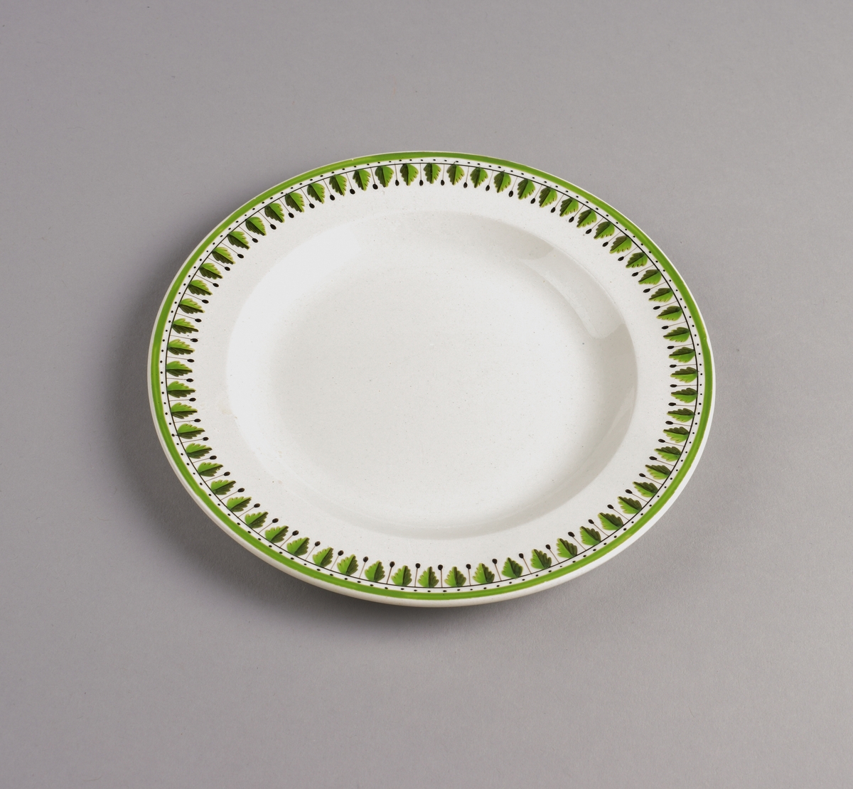 Stilisert borddekor i to grønnfarger langs kanten.