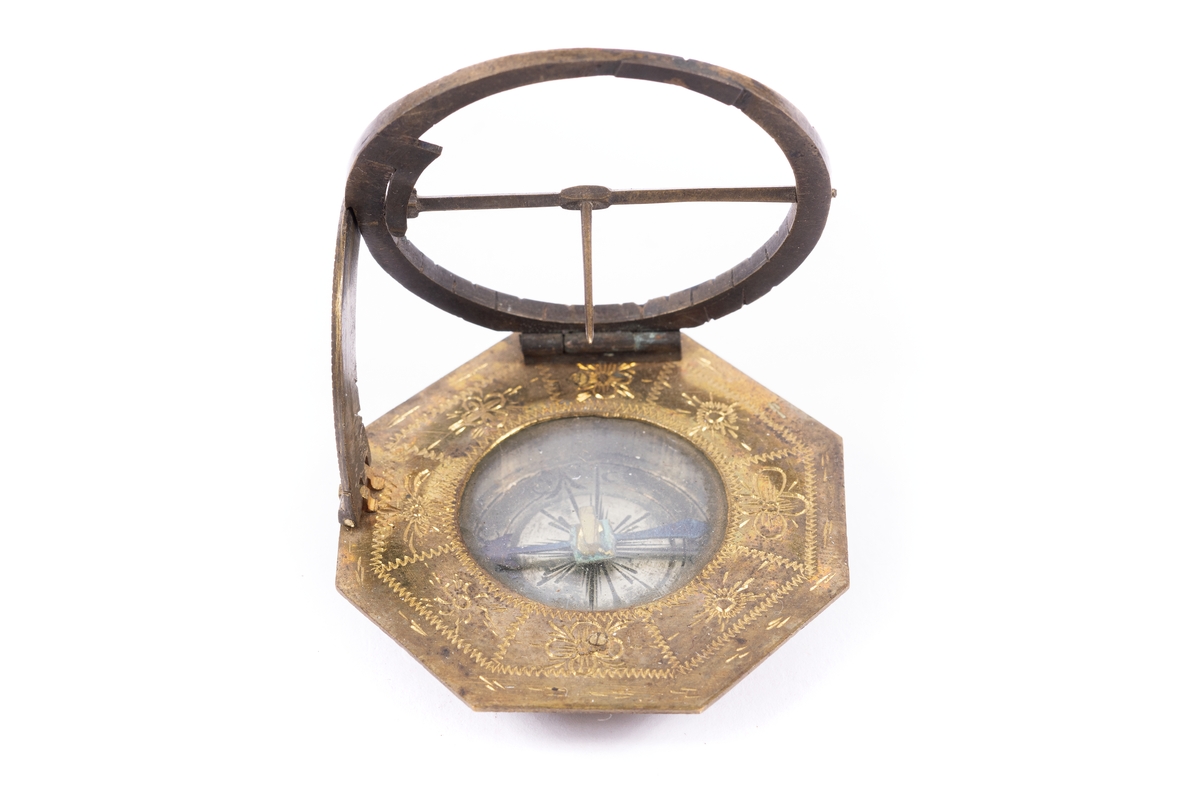 Solur med kompass, rosen orienterad för ca 10 grader västlig missvisning. Båge för polhöjd försilvrad. Etui 8-kantigt, svart läder.