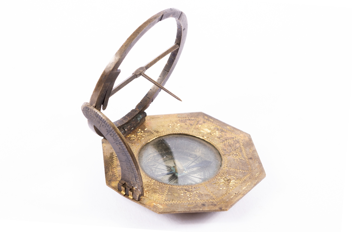 Solur med kompass, rosen orienterad för ca 10 grader västlig missvisning. Båge för polhöjd försilvrad. Etui 8-kantigt, svart läder.