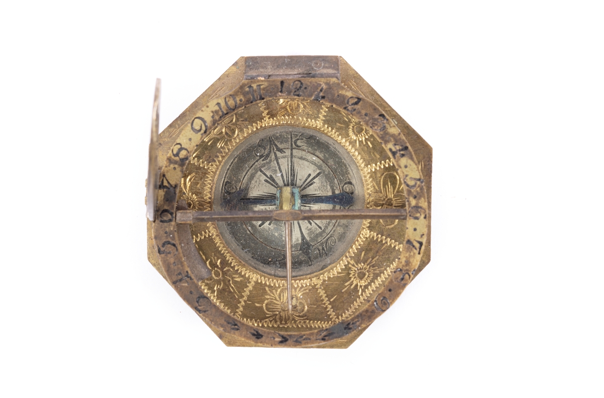 Solur med kompass, rosen orienterad för ca 10 grader västlig missvisning. Båge för polhöjd försilvrad. Etui 8-kantigt, svart läder.