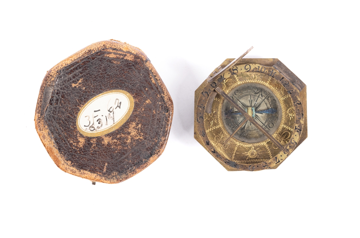 Solur med kompass, rosen orienterad för ca 10 grader västlig missvisning. Båge för polhöjd försilvrad. Etui 8-kantigt, svart läder.