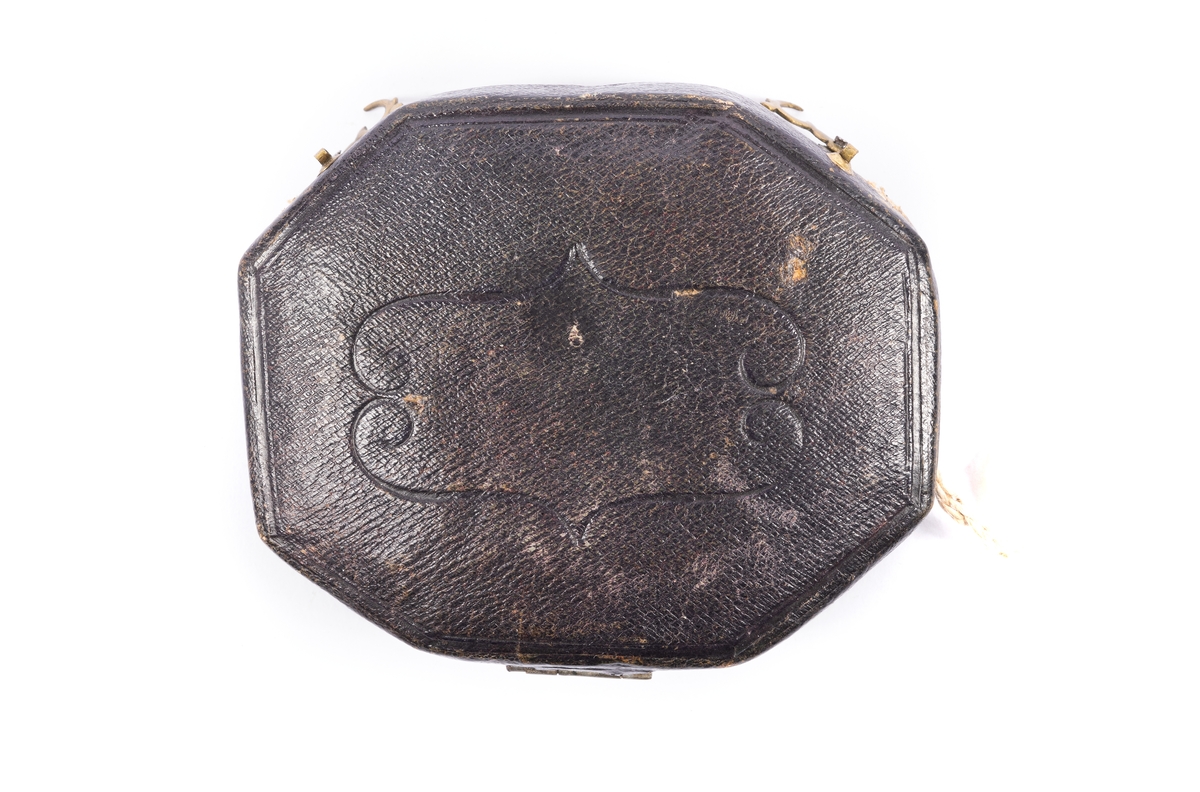 Solur och kompass av mässing. Oval åttkantigt solur med kompass under glas och en solvinkel. Graverad urtavla. Den utfällbara gnomonen (pekaren) är dekorerad med en sittande fågel justerbar för breddgraderna 40-50-60 graderInskription på baksidan: "Toulouse, Tours, Rouen, Turin, Peking, Paris, Amiens, Brest, Caen, Calais, Genes, Lyon, Madrid och Rom." Signerad "Butterfields, A Paris". Läderfodral fodrat med röd sammet.
Från omkring 1700.