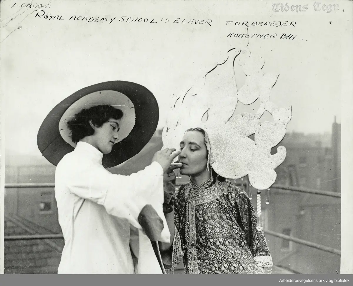 "London: Royal Academy School of Art's elever forbereder kunstnerball. Prinsesse liljedugg får fyr på sigaretten under prøvene." (The Chelsea arts ball) Januar 1933. Arbeidermagasinet/Magasinet for Alle