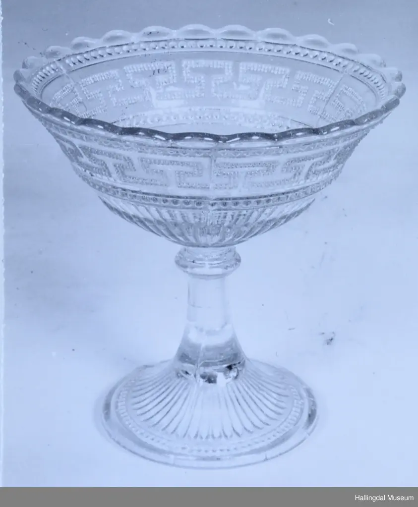 Stettefat, sukkerskål. Sirkulær åpning, tunget kant. Siden hvelvet mot stett med sirkulært tverrsnitt. Vulst på stetten. Stetten skrår utover til fotring, sirkulær. Perlestav og meanderbord på fat. Riller.
26/6-67. O. Foldøy.