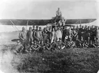 Gruppfoto av militärer med flera vid spanarskolan på Stora Lund, Hästholmen framför flygplan Phönix Dront, hösten 1921. Den civilklädde mannen i bildens mitt, är Stora Lunds ägare Axel Salmonson omgiven av sin familj.