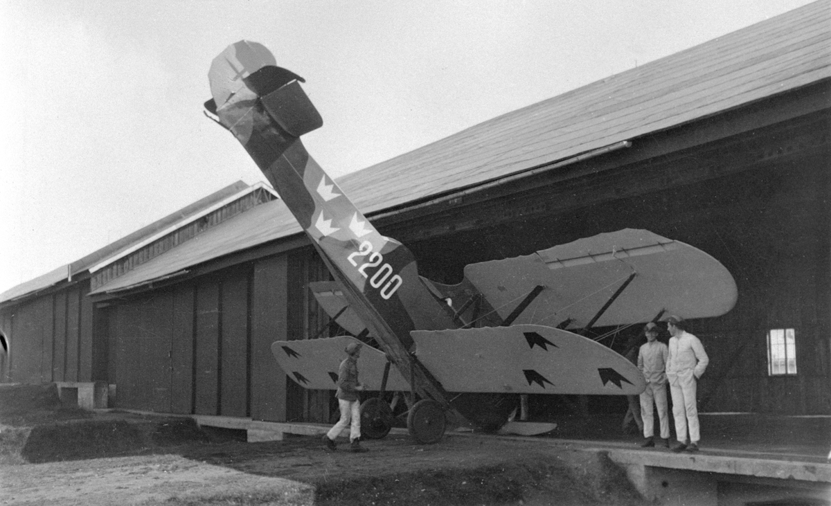 Prototypen till flygplan FVM S 21, nr 2200 står på nosen vid F-hangaren på Malmen. Tre militärer vid planet. Omkring 1923-1926.