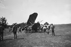 Flygplan FVM Phönix Dront tas om hand efter landningshaveri öster om Malmen, omkring 1920-1926. Militärer och barn vid flygplanet.