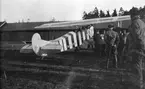 Folksamling vid flygplan Fokker D. VII, som flögs till Malmen 1919 av den tyske stridsflygaren Herman Göring. Flygplanet övertogs av Flygkompaniet och fick nummer 937. Målning innan övertagandet. Vy bakifrån.