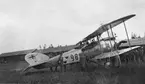 Militärer samlade vid flygplan FVM S 18, nummer 988 på Flygkompaniets tygverkstäder på Malmen, omkring 1919-1922. Vy från sidan. I bakgrunden syns F-hangaren.