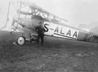 En flygmekaniker står vid flygplan FVM S 18, nummer 0112, civilregistrerat S-ALAA under Internationella luftfartsutställningen i Göteborg, ILUG 1923. Flygplanet var låneköpt och registrerat på löjtnant Hugo Montgomery för deltagande flygning Rotterdam-Göteborg 1923. Haveri i Rotterdam varvid besättningen omkom.