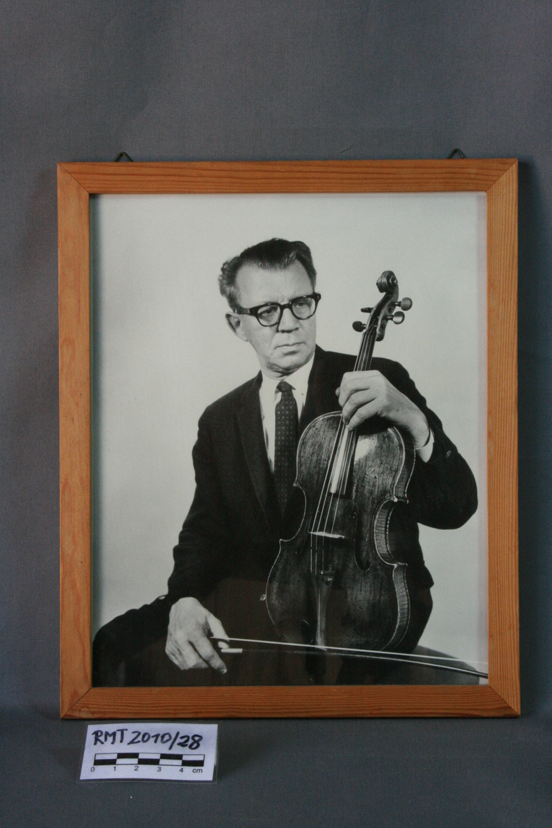 Mannsperson, sittende, med bratsj i hånden.