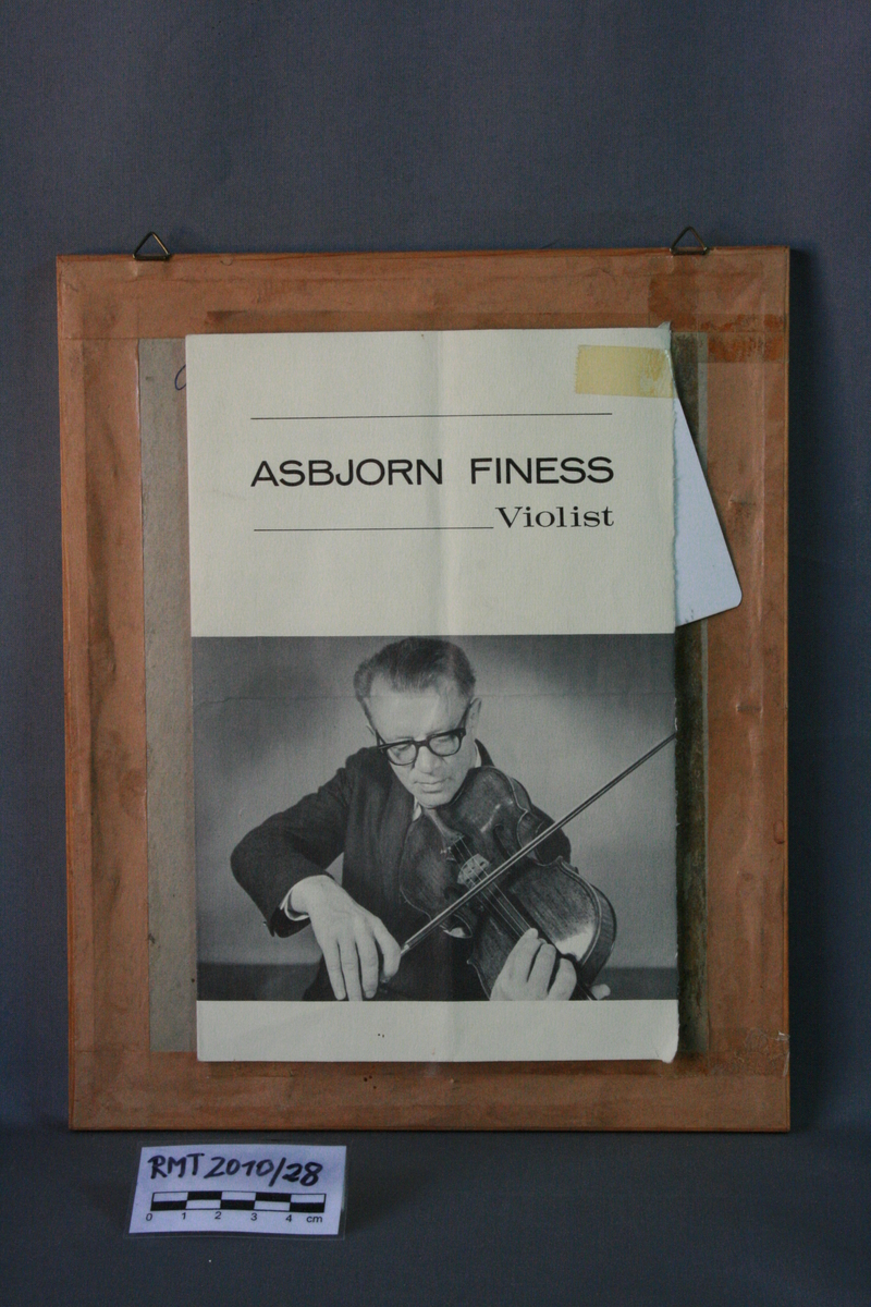 Mannsperson, sittende, med bratsj i hånden.