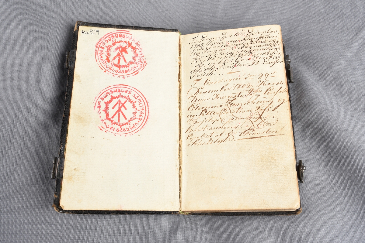 Skinninnundet bok, rektangulær form. Gulldekor preget inn i skinnet på bokens omslag. Papiret i boken har gullfarget dekor ytterst på alle sidene slik at når boken er lukket kommer gulldekoren til sin rett. Preget dekor på kortsidene av papiret. Boken lukkes med to beslag.