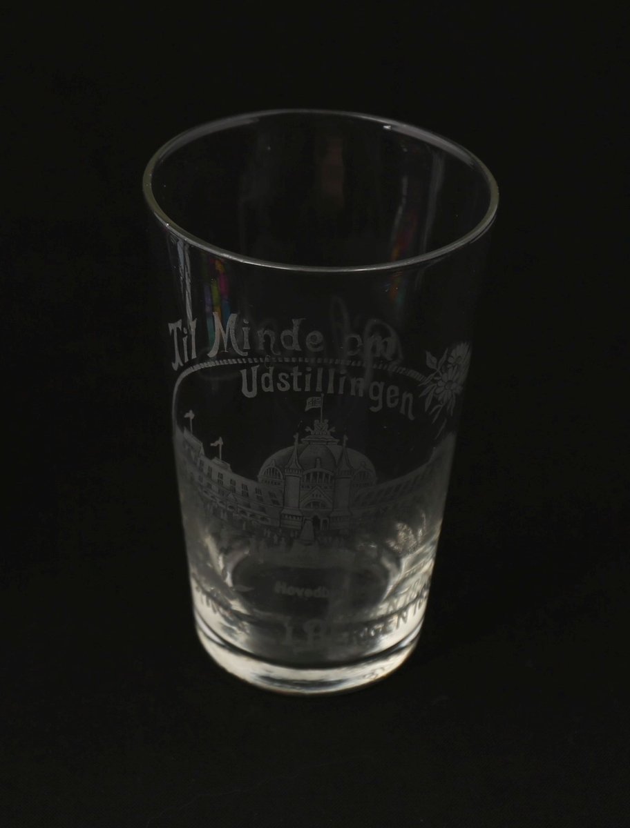 Drikkeglass produsert som minnegave fra Bergensutstillingen i 1898. På korpus er det malt på tegning av utstillingens hovedpaviljong sammen med tekst i lys grå farge.