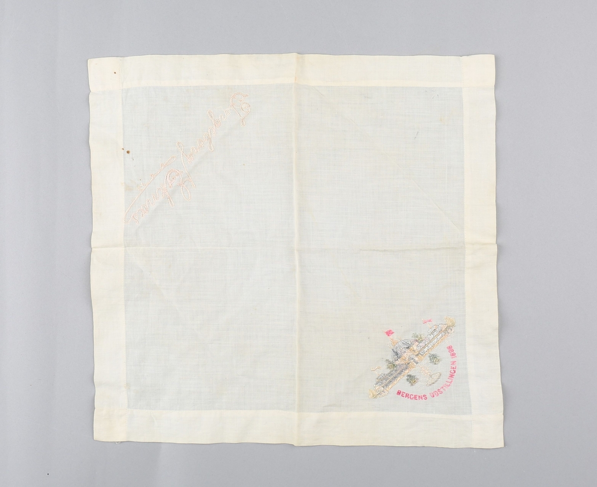 Tekstilserviett med brodert motiv av hovedpaviljongen på Bergensutstillingen i 1898. Også brodert et navn. Servietten er faldet med maskinsøm