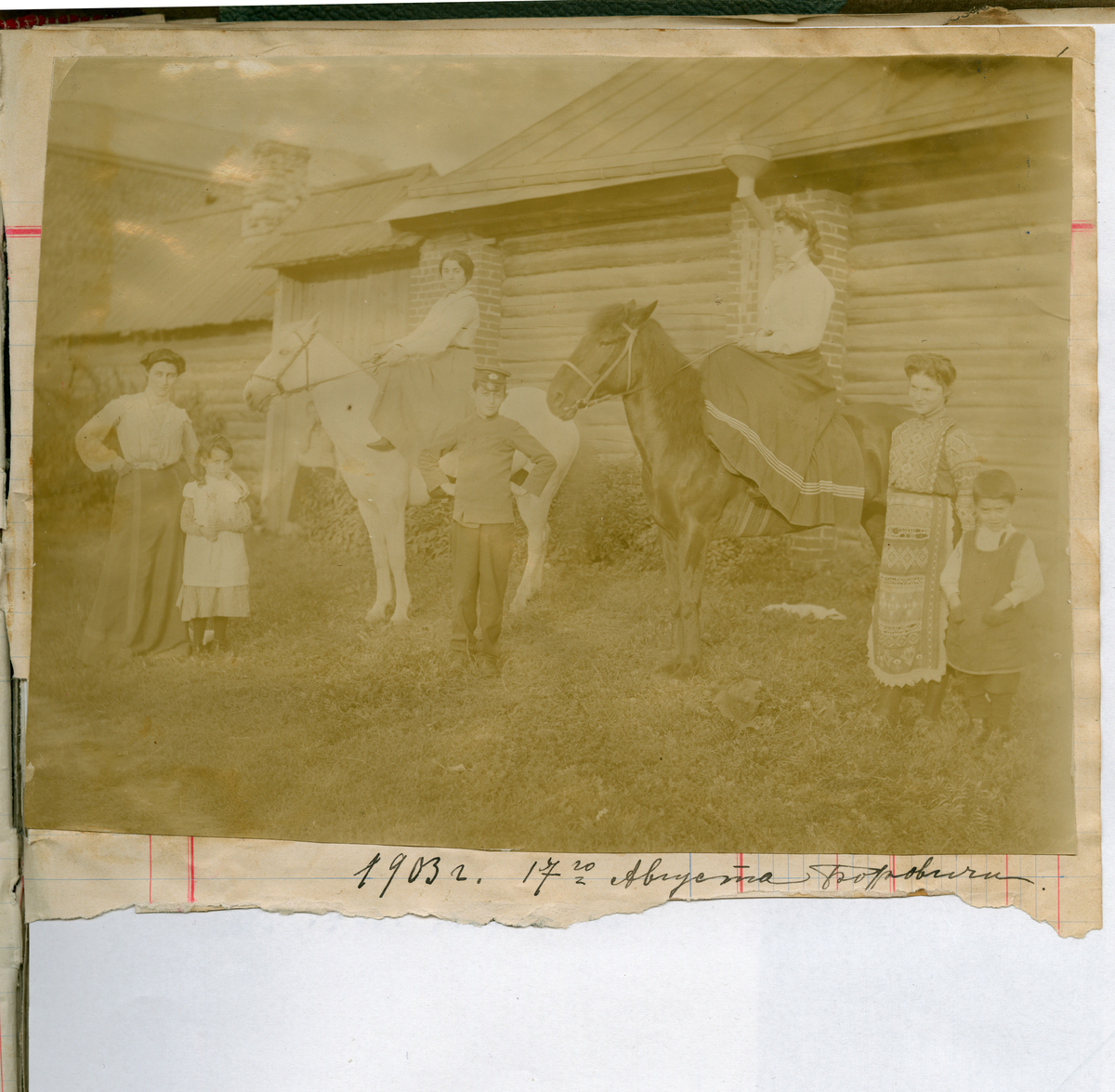 Side tolv i Florentine Rostins fotoalbum (eldre søster av Victoria Bachke), trolig påbegynt i 1903. Bildene er limt inn i en regnskapsbok.
Bildet viser syv personer og to hester. Familien Rostin i Borovichi, 1903. Til hest, fra venstre: Elisabeth og Valentine.
Foran, fra venstre: Florentine, Serafima, Ignazy, Julia og Nikolaj.