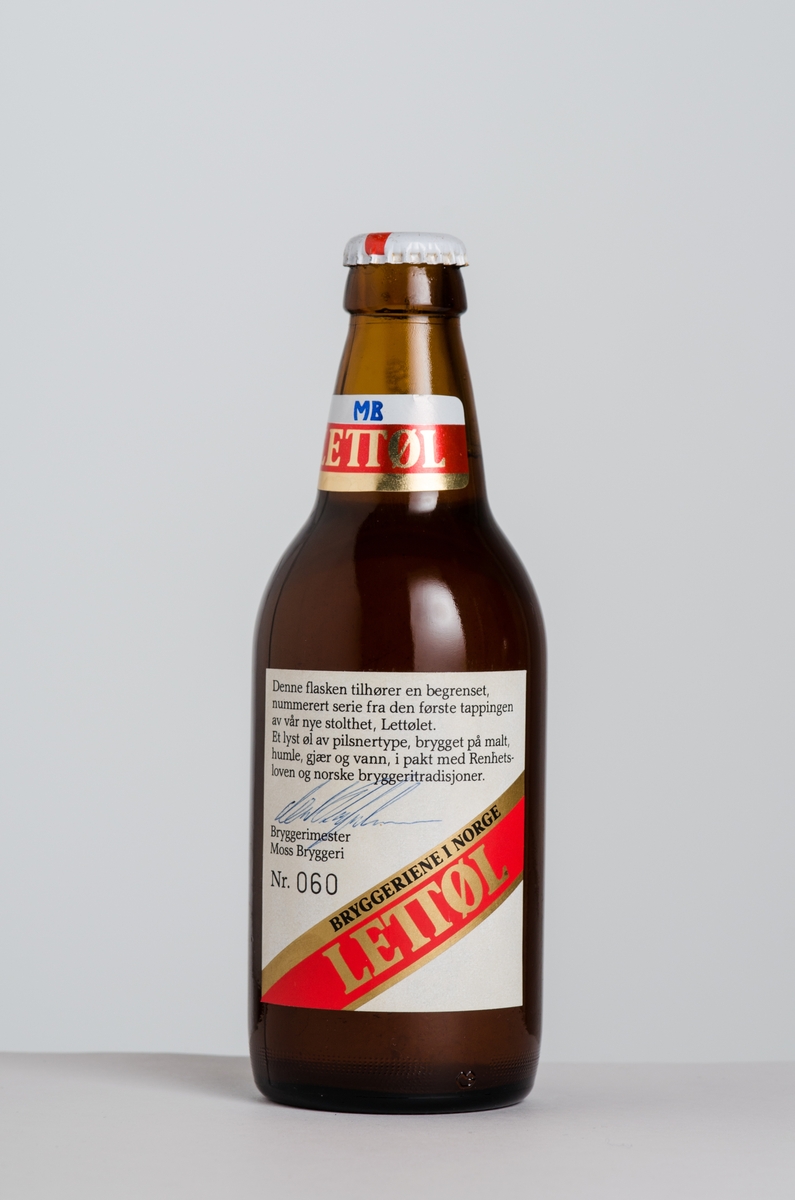 Brun lettølsflaske med emballasje og et jubileumsbånd.