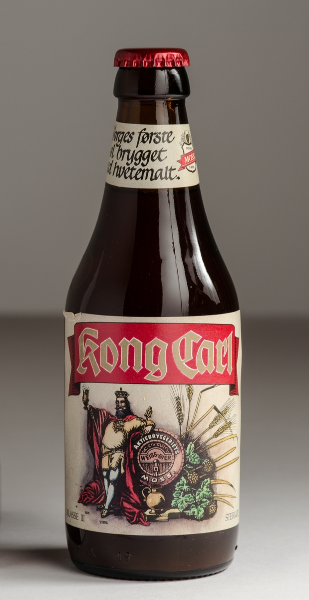 Ølflaske i brunt glass med rød crown cork og etikett foran og bak. Liten etikett på halsen.