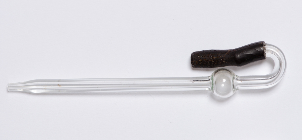 Rektangulær, sort, kube med hengslet lokk og lukkekrok. Pipette i glass med endestykke i gummi. Porselensfat med seks sirkulære fordypninger.
Kork til karaffel (selve karaffelen sitter fast i boksen) Korken er slipt i enden med gripetak formet som to ører og horisontal tapp.