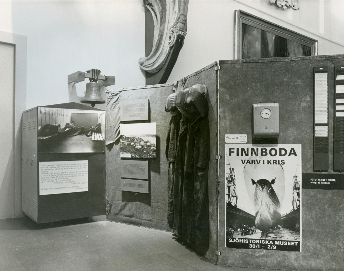 Utställningen "Finnboda varv i kris". Utställningsinteriör med fotografier, stämpelur, arbetskläder m.m.