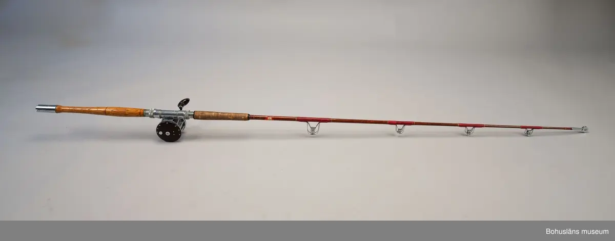 Havsfiskespö i glasfiber med havsfiskerulle för pigghaj och rocka.
Havsfiskerulle av märket True Temper.
På spöet en klisterlapp med tidningen Expressens logo, en geting.