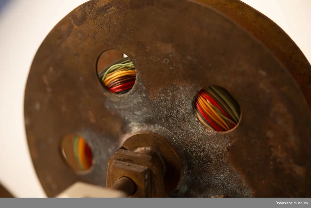 Hemmagjor manuell djuprigg. Fast bom av mässing och rulle av metall och vev med korkhandtag fästad mot en gråmålad bottenplatta. 
På rullen sitter flerfärgad nylonlina. I bottenplatta urtag för spö. Tejpad med grå tejp.
Räkneverk för  - troligen - antalet vevtag.