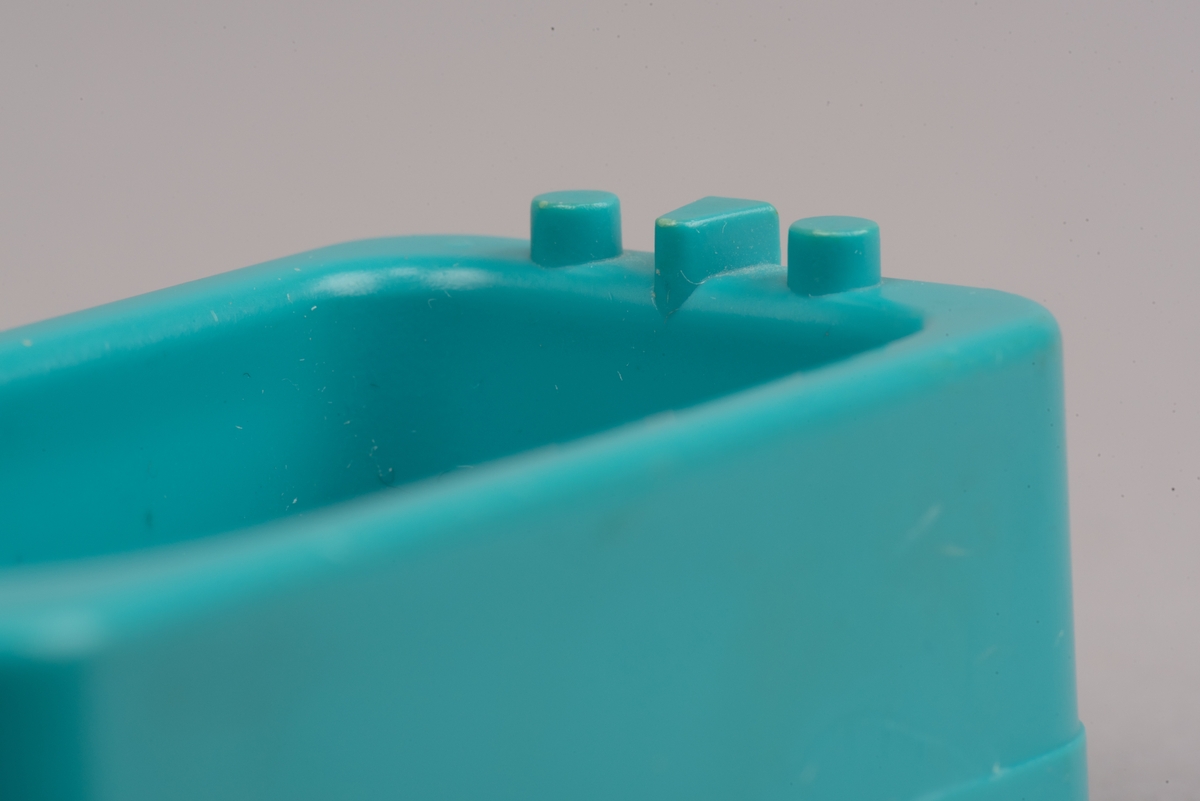 Dockskåpsmöbel i form av ett badkar tillverkat av plast.
Badkaret är rektangulärt i turkos färg. I botten finns ett avrinningshål och på den ena kortsidans övre kant sitter två kranar och en blandare, mycket förenklade i formen.