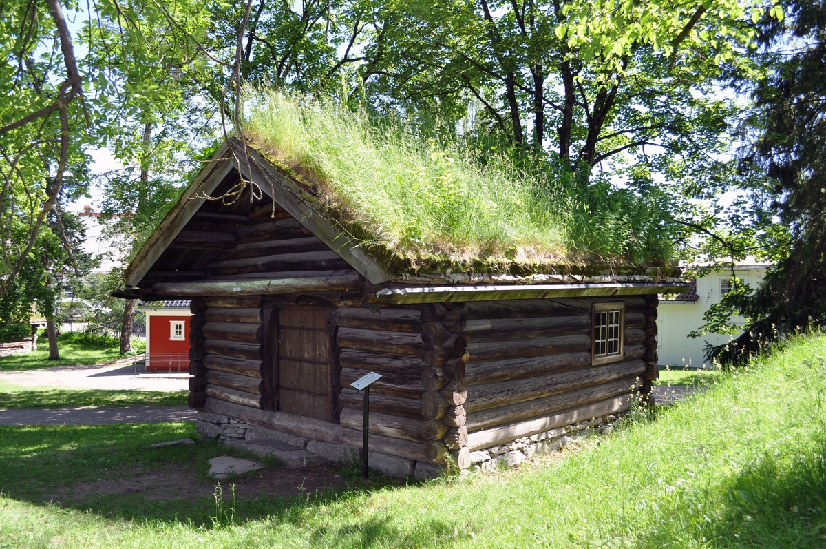 BERGE ELDHUS
Fra Berge, Miland i Tinn. Byggeår: Sen middelalder (1260). 

Eldhuset har opprinnelig vært en årestue med med ett rom. Laftemåten, formen på tømmeret og utformingen av dørpartiet daterer huset til senmiddelalder. Den nåværende takkonstruksjon og utskotet over døra synes å være av yngre dato. Stua har fått installert peis ant. på 16- eller 1700-tallet og små (blyglass-) vinduer, som sporene i veggen viser. Vinduene med tresprosser er ant. fra 1800-tallet.

Den gamle stua ble degradert til eldhus da gården fikk ny og større stuebygning. Eldhusets funksjon på gården kan sammenlignes med bryggerhusets og grovkjøkkenets i bynære strøk. Her ble det vasket, bakt og gjort opp kjøtt- og fiskemat. Navnet henspeiler på ilden, som var viktig for alle slike funksjoner og gjøremål.


THE BERGE FIREHOUSE
From: Berge, Miland in Tinn (Northeast Telemark). Constructed in the late Middle Ages. Rebuilt at the museum in 1962.

The firehouse has originally been an open-hearth cottage with one room. The way the timber is notched, the shape of the timber and the shape ov the doorway dates the house to the late Middle Ages. The present day roof construction appears to be of a newer date. The old cottage was downgraded to firehouse when a larger house was built on the farm.

The function of the firehouse can be compared to theat of the wash-house and the scullery in urban areas. Here there would be washing, baking and preparation of meat and fish. The name indicates the fire, which was important for all such duties and tasks.