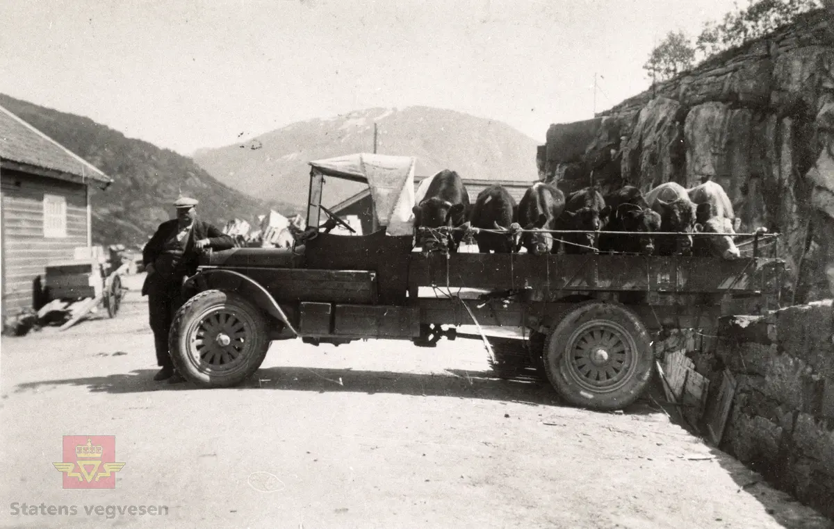 Dette er en amerikansk lastebil. 
Fjordens billag, forløperen til Firda billag, kjøpte en Opel lastebil i 1913. Da Firda billag ble stiftet tidlig på 20-tallet ble enda en 1913 Opel lastebil inkludert. Den var privat eid før det. Firda billags første lastebiler var således Opel. (Opplysninger om kjøretøyet fra Trygve Krogsæter).

Motivet er frå båtstoppestaden Steinen i Førde og framom står sjåfør Einar Bruland. Dette er truleg ein av dei første lastebilane som Firda Billag hadde. Einar Bruland vart tilsett i 1921. (Kjelde: Boka "Transport mellom fjordar, Firda Billag 1920-1995, av Finn Borgen Førsund)