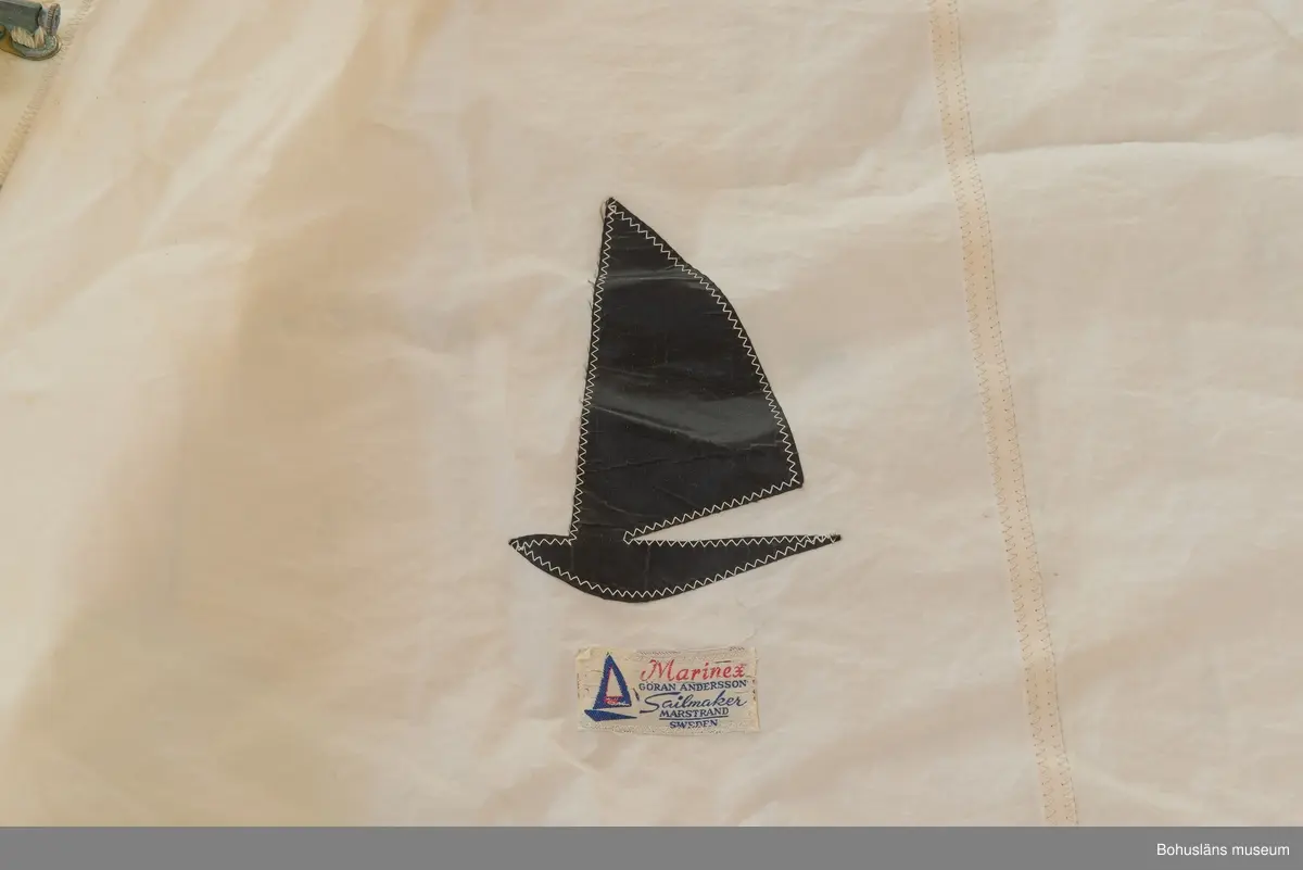 Försegel av dacron förvarat i gul segelsäck.
Märkt Marinex och svart logo.
Rostfri ring i fallhorn, bronsringar i övriga horn. Fem pistolhakar av brons.
Enstaka rostfläckar.
