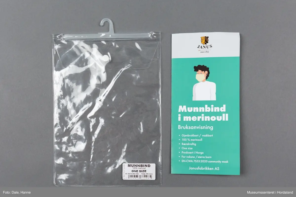 Munnbind i fleire lag strikka stoff i merinoull, med Janus- merke og elastiske stroppar til å feste det med. Munnbindet er pakka i plastemballasje med knappelukking, og det er lagt ved eit informasjonshefte om korleis ein skal bruke det.