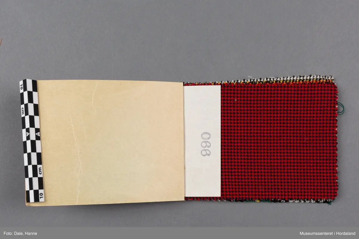 Mappe med rektangulære stoffprøver av vevd ullstoff frå ullvarefabrikken ved Arne Fabrikker. Desse er til kjoletøy i houndstooth/tartan-mønster.